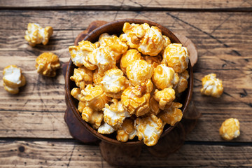 Popcorn in caramel glaze in wooden plates on a rustic table. Copy space.