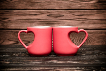 two heart shaped mugs with tea on brown background
