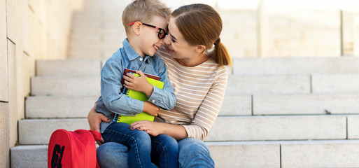 Happy mother and son hugging on steps after school.
