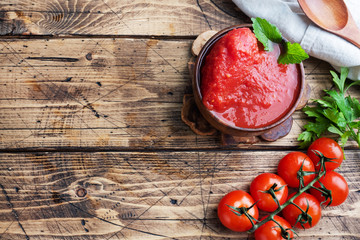 Tomatoes in their own juice or Tomato paste in a wooden bowl and fresh tomatoes on a rustic wooden...