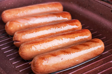 Juicy sausages roasted on the grill pan. Close up.