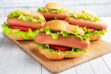 a few hot dogs on a wooden Board. Hot dog with lettuce tomato and sausage. Copy space.