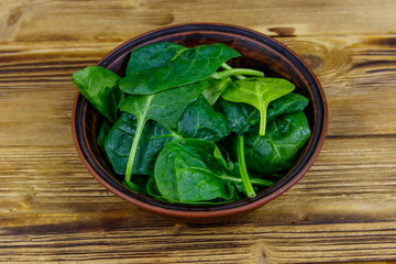 Fresh green spinach leaves in bowl on a wooden table