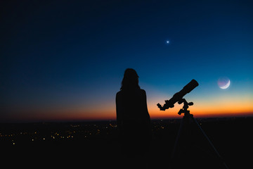 Fototapeta na wymiar Silhouette of a woman and telescope with twilight sky.