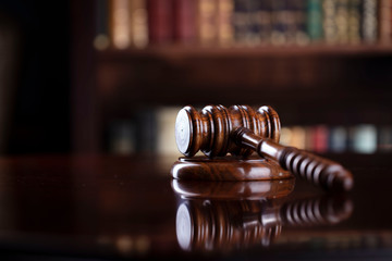 Judge‘s gavel on brown shining table and bookshelf background. Law and justice concept.