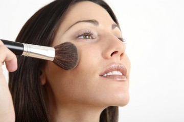 Woman applying blusher on her cheek