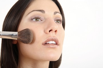 Woman applying blusher on her cheek