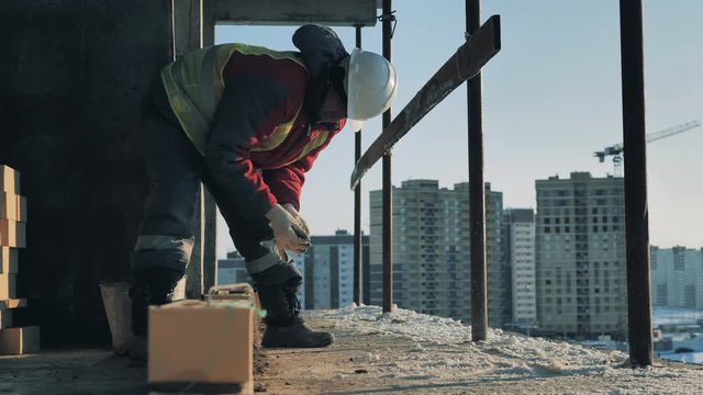 A worker is fixing bricks in lines in a multistory house in progress
