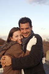 Man and woman in winter clothing hugging at the rooftop