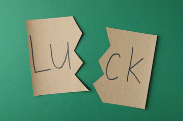 Cut paper with word LUCK on green background, flat lay