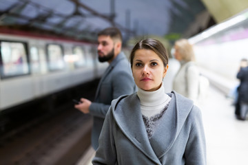 Attractive brunette waiting for train on platform of underground station ..