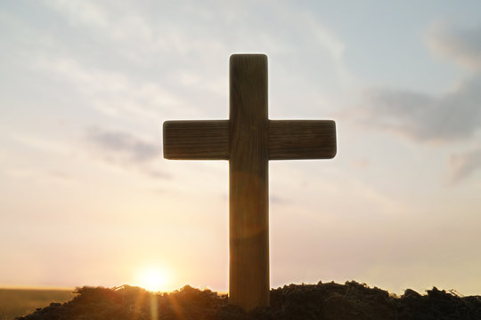 Wooden Christian cross outdoors at sunrise. Religion concept
