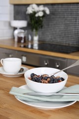 A bowl of breakfast cereal and a cup of coffee on the kitchen counter