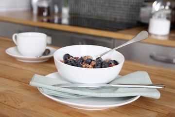 A bowl of breakfast cereal and a cup of coffee on the kitchen counter
