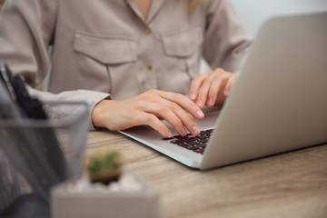 Young woman working with laptop at table, closeup