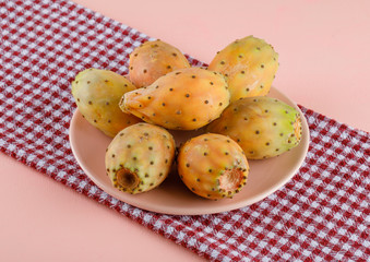 Prickly pears in a plate high angle view on pink and picnic cloth background