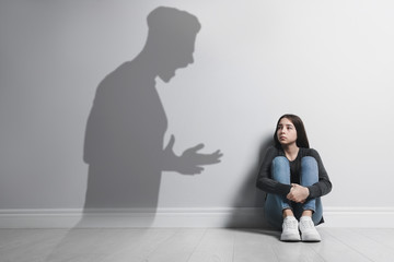 Child abuse. Father yelling at his daughter. Shadow of man on wall