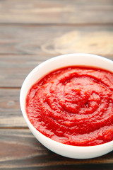 Bowl of ketchup or tomato sauce on brown wooden table