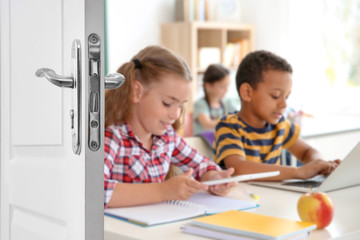 Wooden door open into modern classroom with students