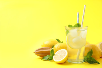 Natural freshly made lemonade with squeezer on yellow background, space for text. Summer refreshing drink