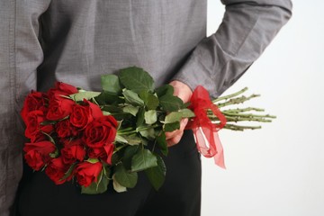 Man holding bouquet of flowers behind his back