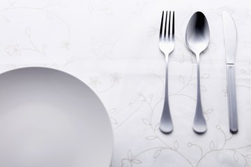 Place setting of fork, spoon and table knife beside plate