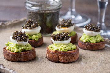 Sandwiches on Borodino bread with avocado paste, quail egg and black caviar