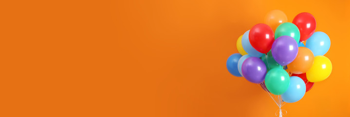 Bunch of bright balloons on orange background, space for text. Banner design