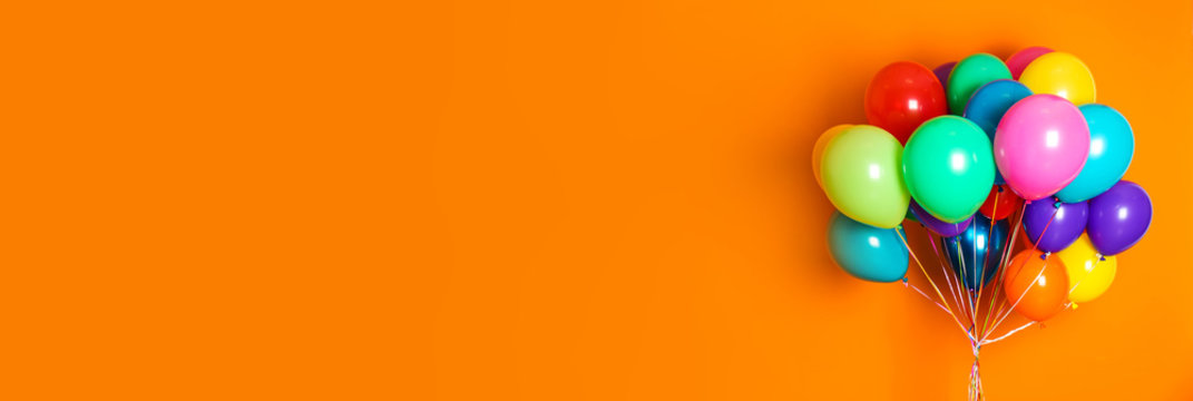 Bunch of bright balloons on orange background, space for text. Banner design