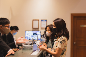 Woman in protective mask checking in at hotel reception new normal.