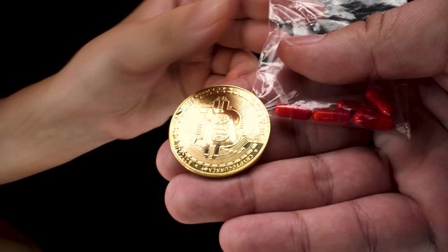 wide-angle macro view of Bitcoin cryptocurrency being used to buy black market drugs, a small transparent bag with red pills on black background 4k