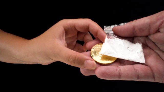 wide-angle macro view of Bitcoin cryptocurrency being used to buy drugs, a white bag of powder sugar representing cocaine on black background 4k