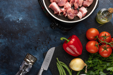 Fresh pork is fried in a skillet on a background of vegetables, with space for an inscription, cooking and a book of recipes
