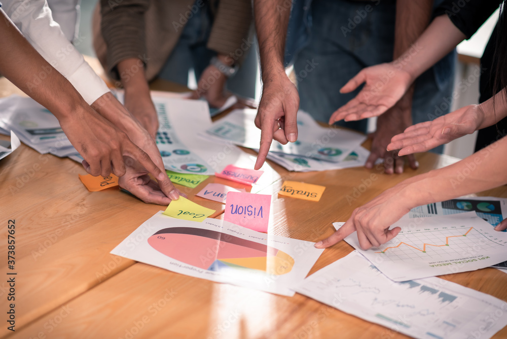 Wall mural hands of six people on meeting table point and brainstorming on post it paper and chart