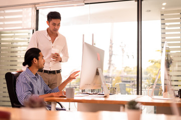 Fototapeta premium Two office worker discussing business on desktop computer
