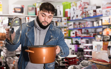 Attentive buyer inspects new pot in a hardware store. High quality photo