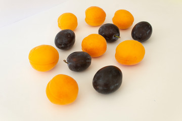 close up fresh ripe garden orange apricots and dark plums fruit on  white background