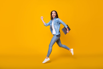 Fototapeta na wymiar Full length body size view of her she nice slim cheerful cheery glad girl jumping running carrying laptop active lifestyle time management isolated bright vivid shine vibrant yellow color background
