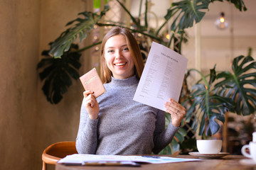 Young happy girl holding passport and visa application, sitting at cabinet.