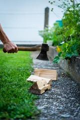 Mann hackt Brennholz mit einer Axt im Garten. Wiese, draußen, Vorrat.