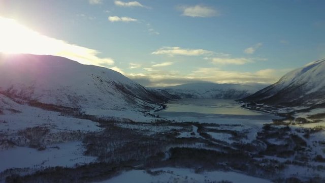 Aerial Pan shot of Norwegian Fjord winter landscape at sunset