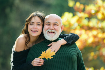 Portrait of young woman embracing her father in autumn park.