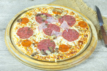 pizza au chorizo, salami et bacon sur une planche à découper