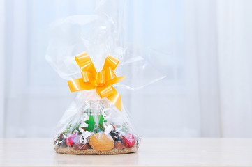 A Christmas gift in a transparent package with a bow on table. White background.