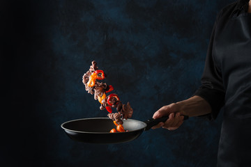 Chef cooking octopus seafood frying in a skillet with vegetables, freezing in motion