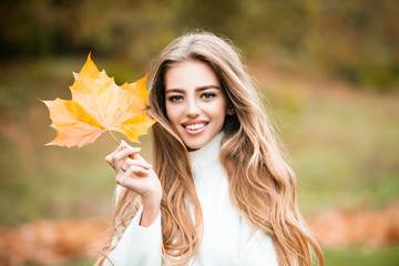Happy Autumn. Young blonde woman portrait in autumnal color.