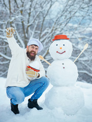 Fototapeta na wymiar Excited Christmas chef cook. Snowman and funny bearded man in the snow kitchen. Joyful Father cook Having Fun with snowman in Winter Park.
