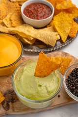 Chips with different snacks with salsa on a light background, close up