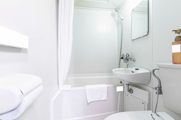 Small bathtub and shower in the bathroom at the hotel.