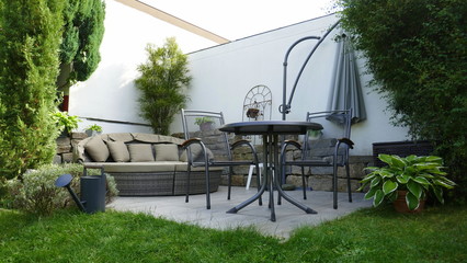 Gartenterrasse mit Lounge- und Sitzgruppe in einer Gartenecke mit Säulen-Faulbaum und umgeben von...